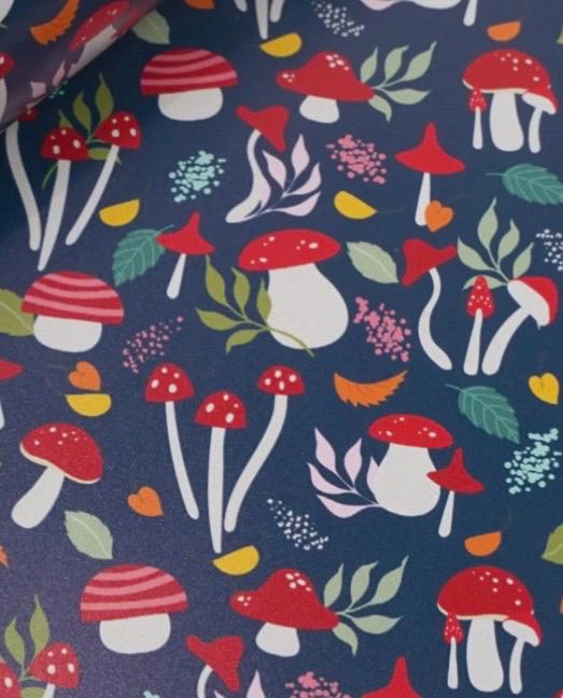 May include: Dark blue background with a repeating pattern of red and white mushrooms, green leaves, and small pink and yellow floral accents. The mushrooms have white stems and red caps with white spots.