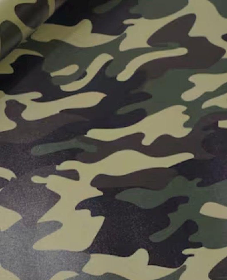 May include: Camouflage pattern fabric in shades of green, brown, and tan. The design features irregular, organic shapes, creating a classic military-inspired aesthetic. The fabric appears to be a durable material, suitable for various applications.