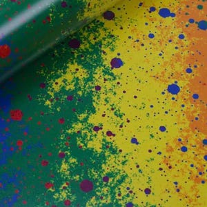 May include: A close-up of a colorful abstract design with a gradient of green, yellow, and orange. The design features splattered paint in red, blue, and purple, creating a vibrant and textured appearance.