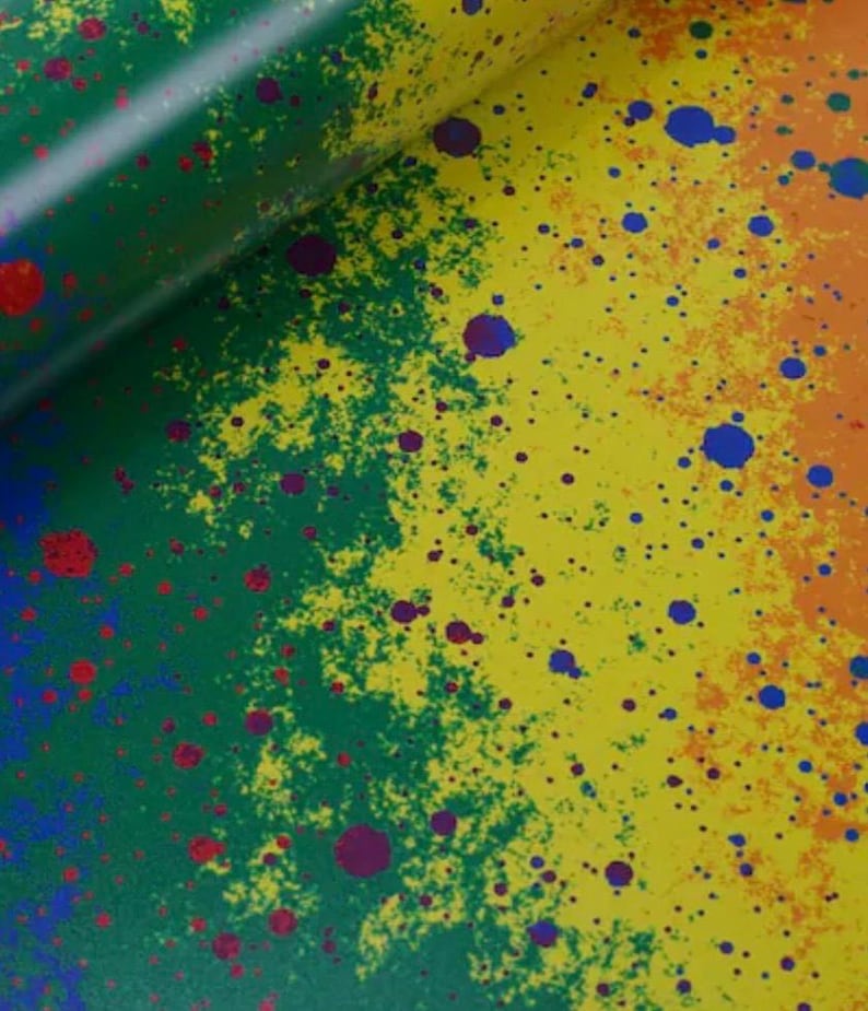 May include: A close-up of a colorful abstract design with a gradient of green, yellow, and orange. The design features splattered paint in red, blue, and purple, creating a vibrant and textured appearance.