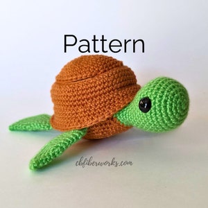 Peut inclure: Une tortue crochetée avec une carapace marron, une tête et des nageoires vertes, et des yeux noirs. Le mot "Pattern" est écrit au-dessus de la tortue. Le site web "cbfiberworks.com" est écrit en dessous.