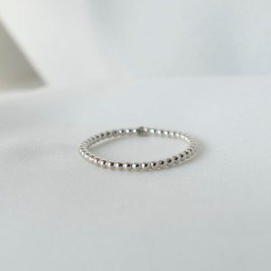 Könnte beinhalten: Ein silberner Perlenring auf weißem Hintergrund.