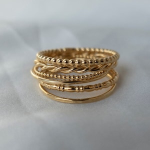 以下が含まれることがあります： ビーズ、ツイスト、ハンマーなど、さまざまなテクスチャのゴールドスタッキングリング6個セットです。