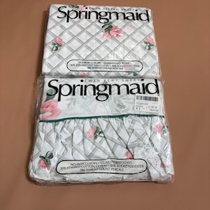 May include: Two Springmaid twin sheet packages in plastic wrap. The top is a fitted sheet, the bottom is a flat sheet with a ruffled eyelet edge. Both feature a white background with a grey lattice pattern and pink floral accents, 180 thread count.