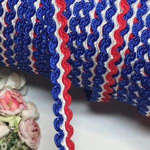 May include: Red, white, and blue scalloped trim. The trim is made of a woven fabric and has a wavy edge.