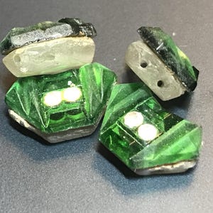 May include: Three green glass buttons with a faceted design and two white pearl-like accents on each button.