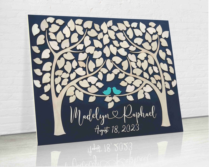 A guest book alternative made on a wood board and with two trees and leaves for guests to sign. the names of the bride + groom are under the trees, personalized per the names of the newlyweds. copyrighted image belongs to SignYouStyle