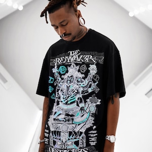 Puede incluir: Camiseta negra con un estampado gráfico de una deidad con múltiples brazos, rodeada de formas geométricas. El texto "THE REMOVER OF OBSTACLES" está impreso en la camiseta.