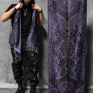 May include: A black and purple shawl with a geometric design and fringe. The shawl is held up to display the intricate pattern. The design includes circles, lines, and symbols. The shawl is worn as a hood.