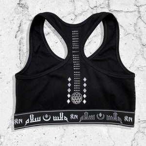 May include: Black sports bra with a white geometric design and the text "RN" and "SALAM" repeated on the bottom band.