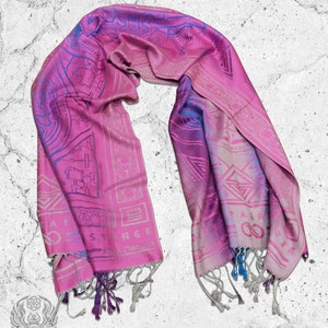 May include: A pink and blue patterned silk scarf with fringe. The scarf has a geometric design and the words "Great Strange" printed on it.