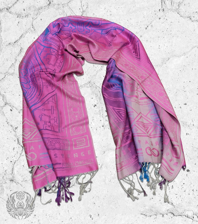 May include: A pink and blue patterned silk scarf with fringe. The scarf has a geometric design and the words "Great Strange" printed on it.
