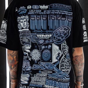 以下が含まれることがあります： 抽象的なデザイン、幾何学的な形、そして「eye tape」と「REPOLICY」というテキストが特徴の、青と白のグラフィックプリントが施された黒いTシャツです。