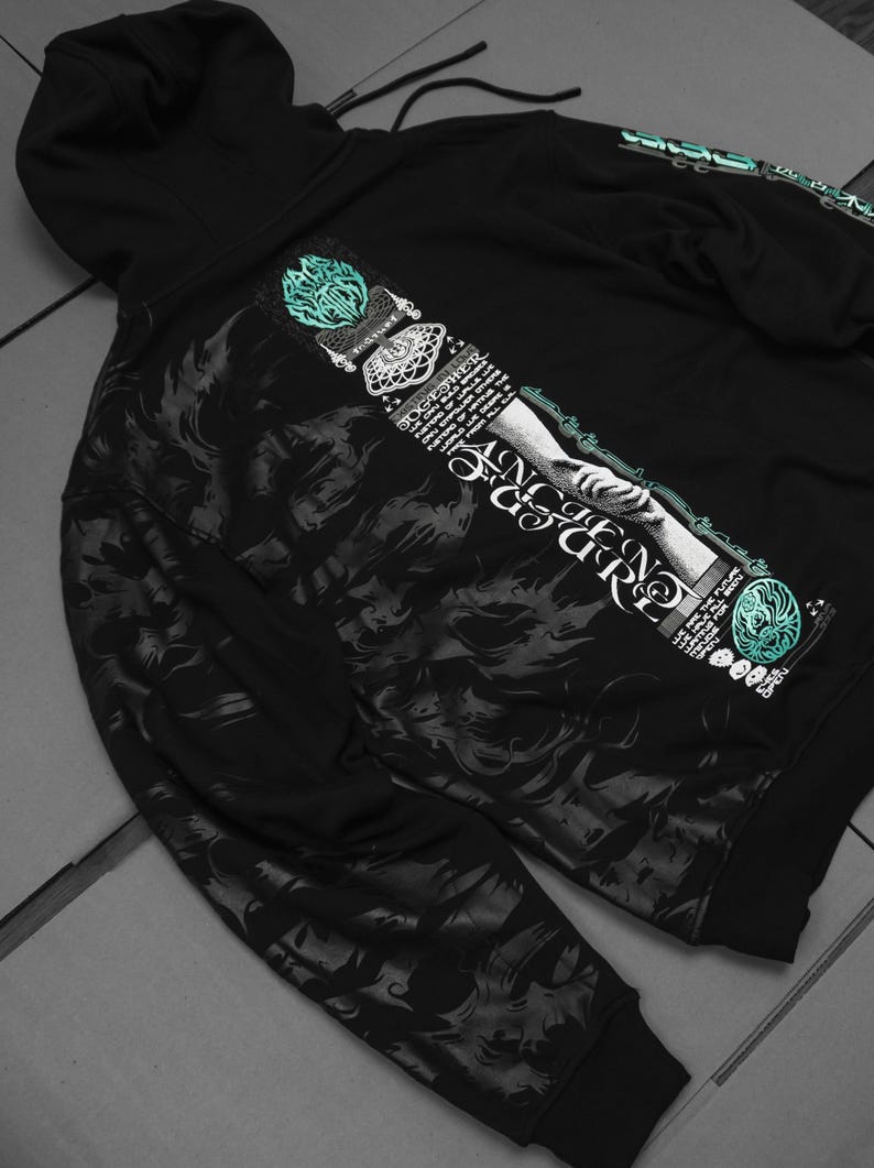 May include: Black hooded sweatshirt with a graphic print of a hand reaching out from a cloud with the text "ANCIENT FIGURE" and other text in a stylized font. The graphic is in shades of gray and teal.