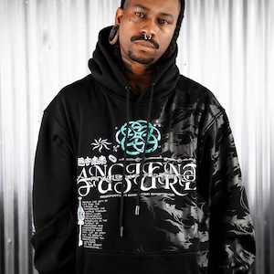 May include: Black hooded sweatshirt with a graphic print of a teal and white design. The design includes the words "Ancient Future" and "Resonante in a Greater Existence".