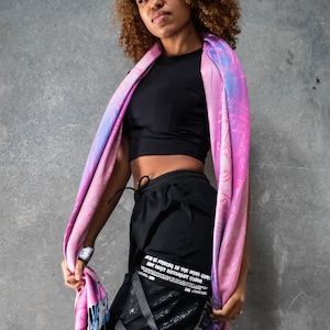 May include: A person wearing black pants with a graphic print and a pink and blue scarf. The pants have multiple straps and buckles. The text on the pants reads "JUST BE PATIENT IN THE GAME, SOME DON'T MAKE IT DIFFERENT TIMES."