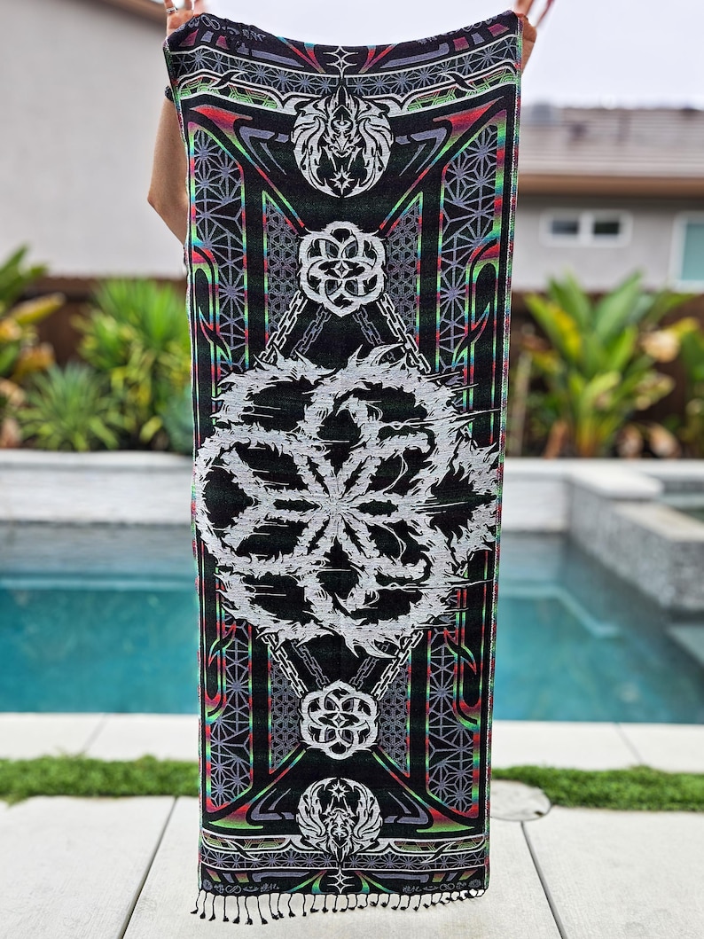 May include: A black tapestry with a geometric pattern. The design includes a large white floral motif, with red, green, and purple accents. The edges are finished with a fringe.