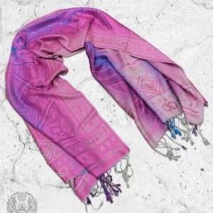 May include: A pink and blue patterned silk scarf with fringe tassels. The scarf features a geometric design with intricate details.