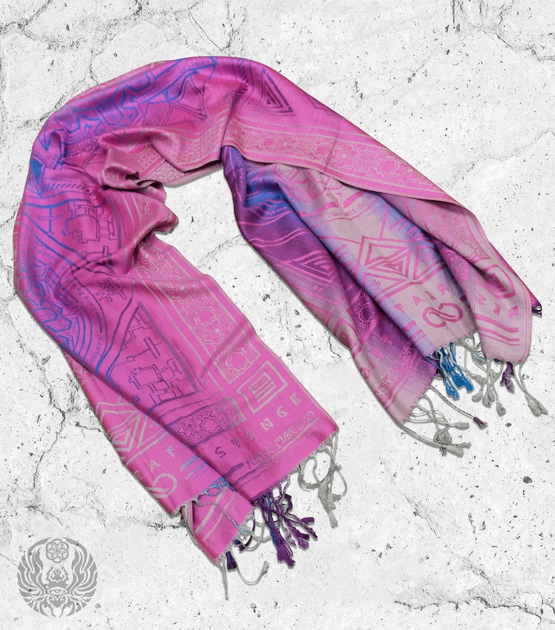 May include: A pink and blue patterned silk scarf with fringe tassels. The scarf features a geometric design with intricate details.