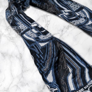 May include: A blue and white patterned scarf with geometric designs. The scarf has a fringe edge and features the text "Rage Nation" in white.