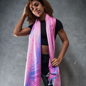 May include: A woman wearing a black top and black pants with a pink and blue patterned scarf. The scarf has a geometric design and is tied around her neck.