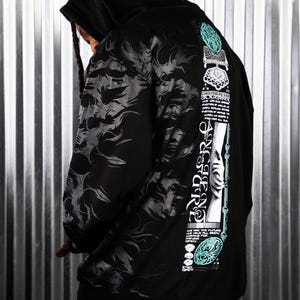 May include: Black hooded sweatshirt with a graphic print on the back. The print features a hand reaching up with the text "EXISTRE IN LOVE TOGETHER" and other text and designs.