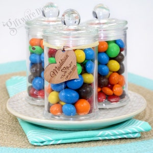May include: Three glass jars with lids filled with colourful candy. The middle jar has a wooden heart-shaped tag with the text "Maddison Skye 13th Dec 2013".