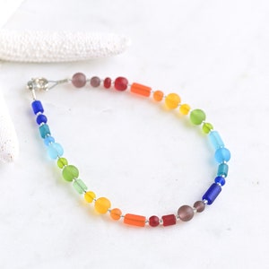 May include: A rainbow-colored glass bead bracelet with a silver clasp. The beads are in shades of red, orange, yellow, green, blue, and purple.