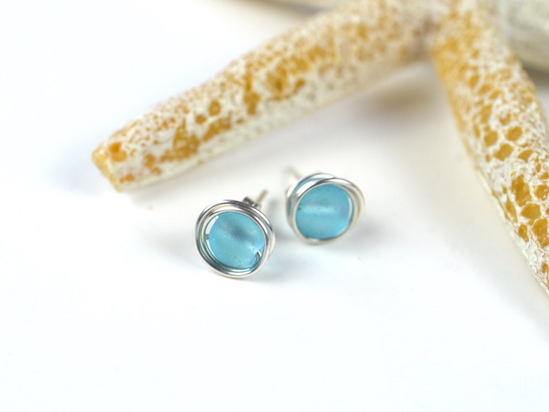May include: A pair of silver wire wrapped earrings with light blue glass beads