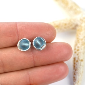 May include: A pair of silver wire wrapped earrings with light blue glass beads.