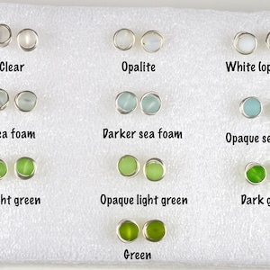 May include: A variety of glass earring studs in different colors, including clear, opalescent, white, sea foam, light green, dark green, and opaque versions of each color. The earrings are displayed on a white background.