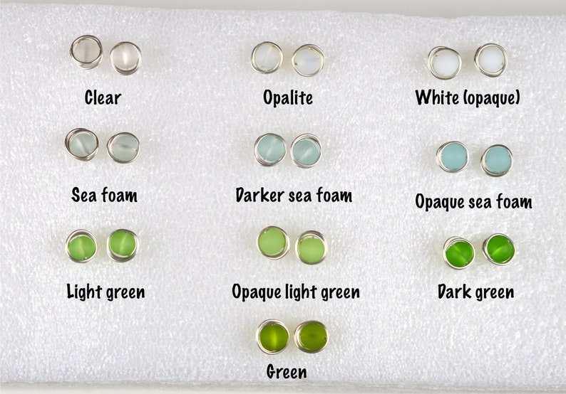 May include: A variety of glass earring studs in different colors, including clear, opalescent, white, sea foam, light green, dark green, and opaque versions of each color. The earrings are displayed on a white background.