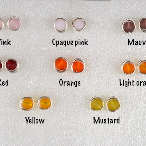 May include: A set of 10 pairs of earrings with different colored glass beads. The colors include pink, opaque pink, mauve, red, orange, light orange, yellow, and mustard.