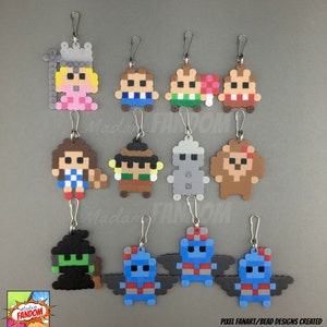 May include: A collection of pixel art keychains featuring various characters. Each keychain is made of colorful beads and includes a silver-tone clasp. The designs include a princess, a robot, and other fantasy figures. The text "Madam Fandom" is visible.