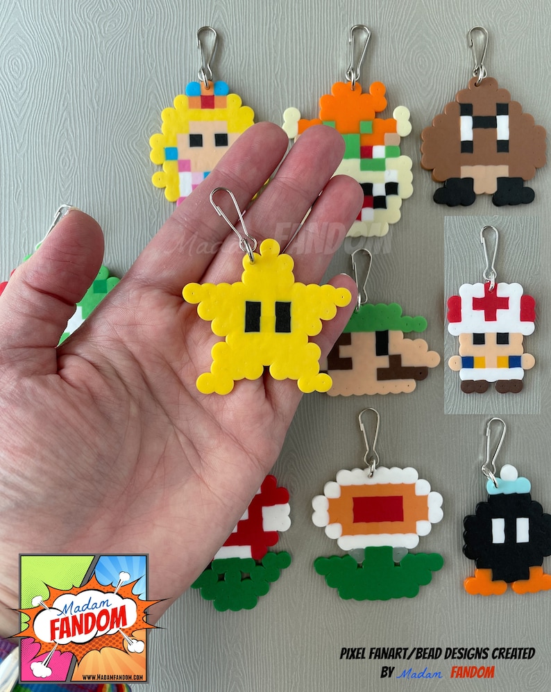 May include: A collection of pixel art keychains featuring characters from the Super Mario video game series. The keychains are made from colorful beads and include characters like Princess Peach, Bowser, and a yellow star. Each keychain has a silver clasp.
