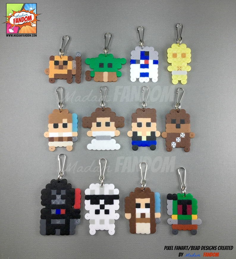 May include: A collection of pixel art keychains featuring characters from a popular science fiction franchise. The keychains are made of colorful beads and include characters like Darth Vader, Yoda, and R2-D2. The keychains have silver-colored clasps.