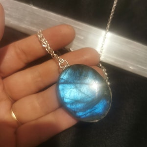 May include: A silver chain necklace with a large oval-shaped blue labradorite pendant.