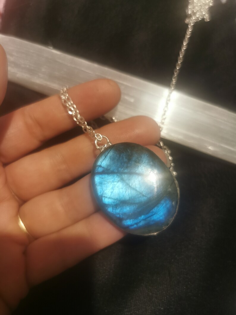 May include: A silver chain necklace with a large oval-shaped blue labradorite pendant.