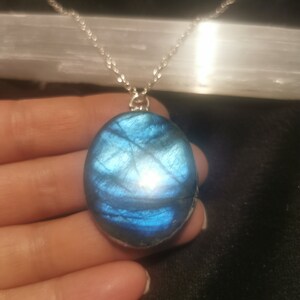 May include: A silver chain necklace with a large oval-shaped blue labradorite pendant.