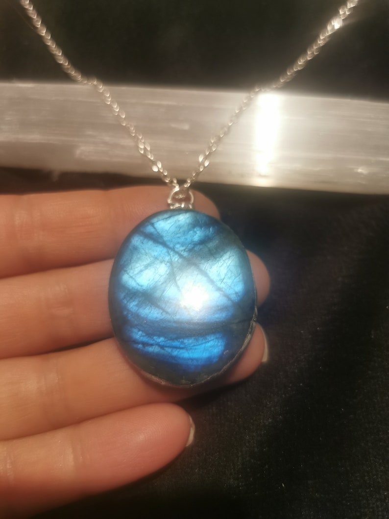 May include: A silver chain necklace with a large oval-shaped blue labradorite pendant.