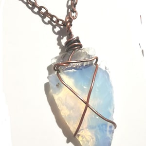 May include: A copper chain necklace with a large, iridescent opal pendant wrapped in copper wire.