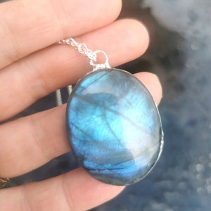 May include: A silver chain necklace with a large oval-shaped blue labradorite pendant.