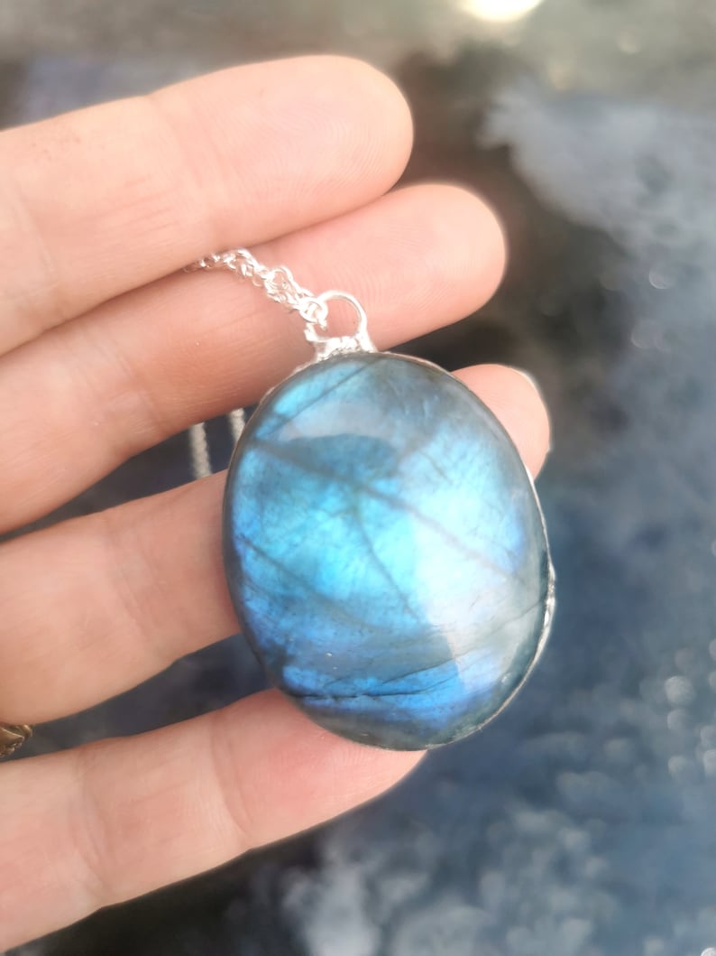 May include: A silver chain necklace with a large oval-shaped blue labradorite pendant.