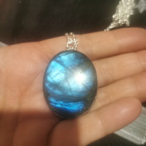 May include: A silver chain necklace with a large oval-shaped blue labradorite gemstone pendant.