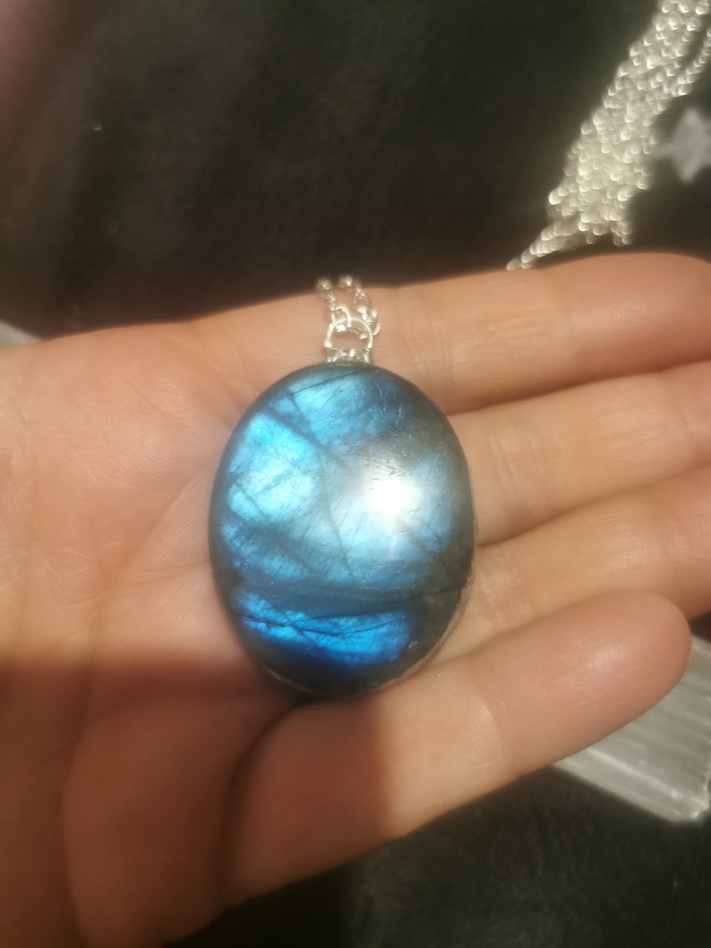 May include: A silver chain necklace with a large oval-shaped blue labradorite gemstone pendant.