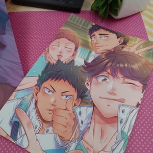 K&ouml;nnte beinhalten: Ein farbenfroher Anime-Print mit vier m&auml;nnlichen Charakteren in einer Gruppenpose. Ein Charakter hebt den Daumen, ein anderer zwinkert. Das Kunstwerk hat eine lebendige Farbpalette und detaillierte Gesichtsausdr&uuml;cke. Im Hintergrund ist eine schwarze Handheld-Konsole zu sehen.