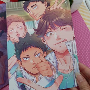K&ouml;nnte beinhalten: Ein farbenfroher Druck im Anime-Stil mit einer Gruppe m&auml;nnlicher Charaktere, die f&uuml;r ein Selfie posieren. Die Charaktere haben verschiedene Ausdr&uuml;cke, darunter Daumen hoch, Friedenszeichen und verspielte Gesichter. Das Kunstwerk hat eine helle und fr&ouml;hliche &Auml;sthetik.
