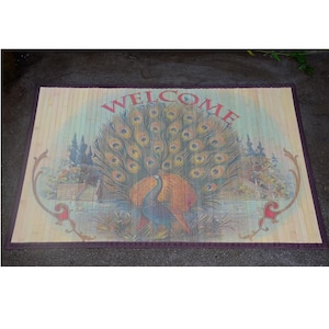 May include: A rectangular bamboo doormat with a peacock design. The peacock is in the center with its tail feathers fanned out. The word "WELCOME" is in red at the top. The mat has a purple border.