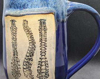 pottery coffee mug with a spine on it in blues or turquoise glaze