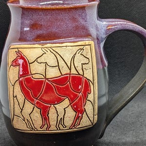 Handmade pottery coffee mug featuring a red llama in blue glaze